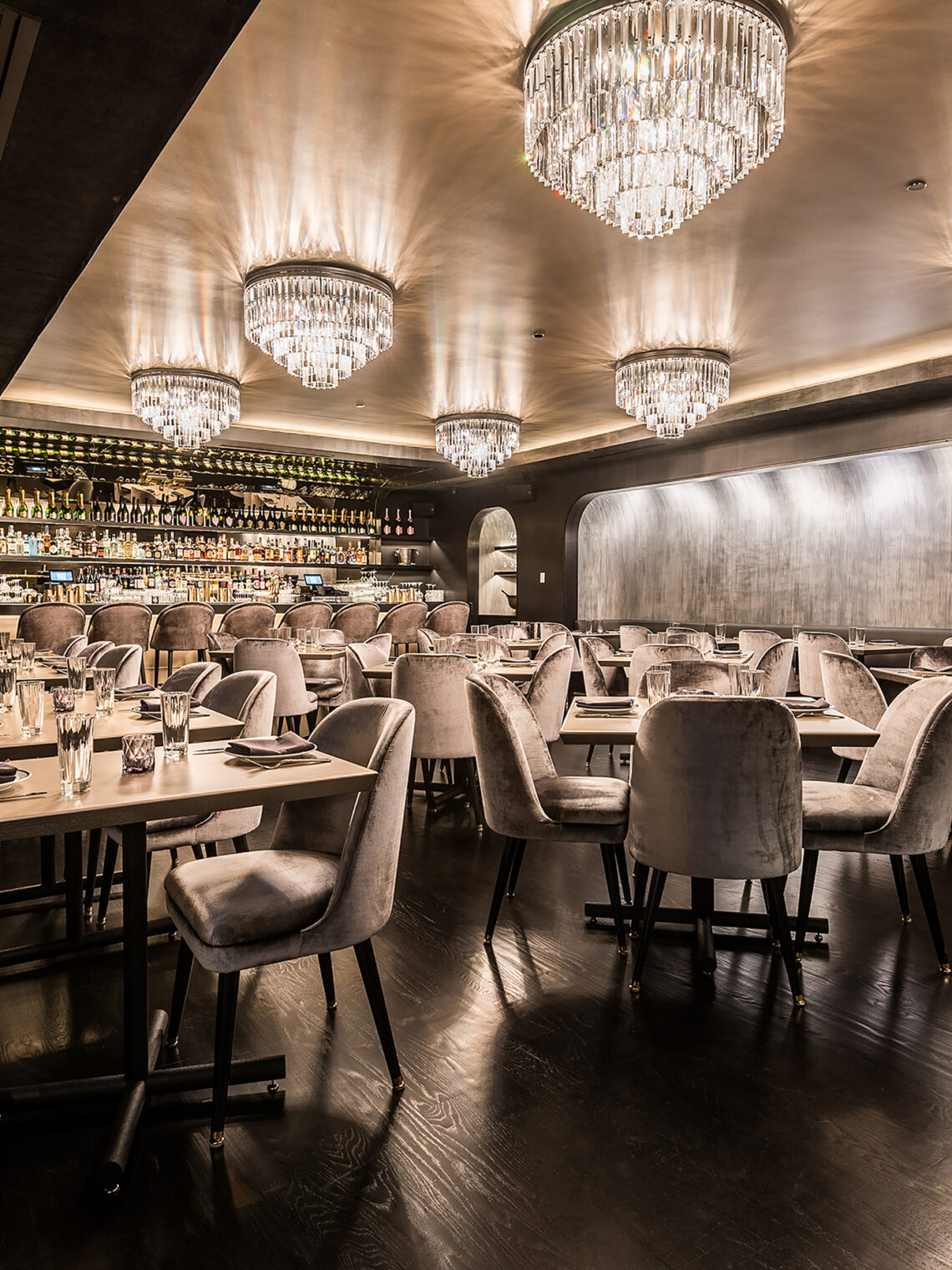Elegant restaurant dining room featuring plush velvet chairs and dramatic crystal chandeliers.
