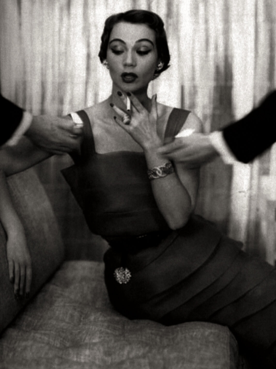 Vintage black and white photograph of a glamorous woman being offered lights for her cigarette.
