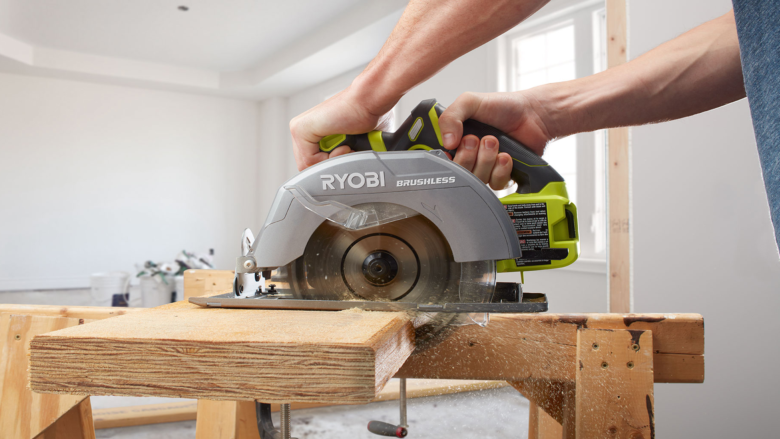 Close-up of a person using a Ryobi brushless circular saw to cut timber.