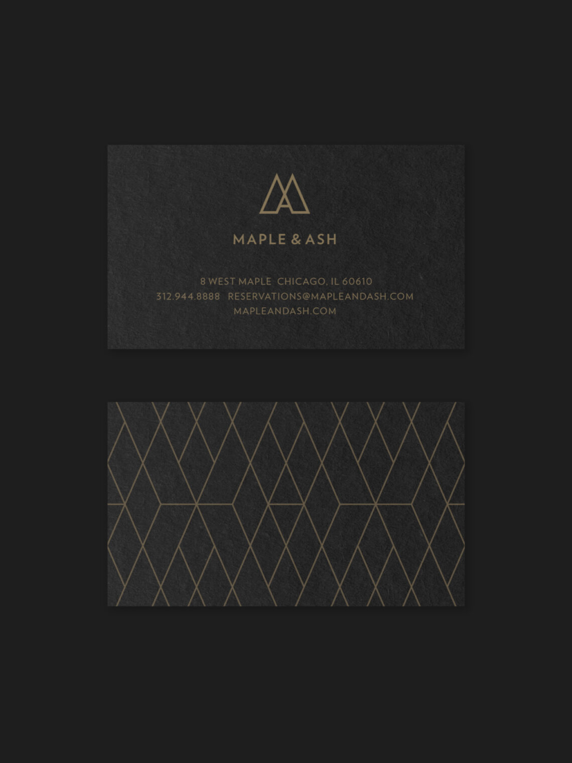 Two black business cards with gold text and geometric lines. The top card shows the MAPLE & ASH logo, address, contact info, and website. The bottom card features a gold geometric pattern on a black background.