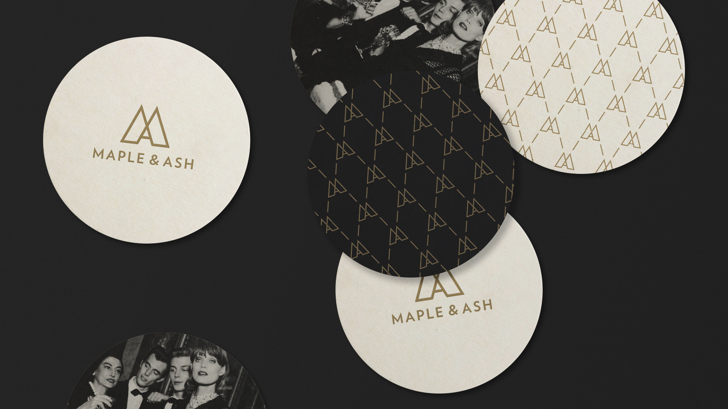 Five round coasters on a dark surface. Two are cream with the Maple & Ash logo and text, two have a repeating gold logo on cream or black backgrounds, and one shows a black-and-white vintage photo of people.
