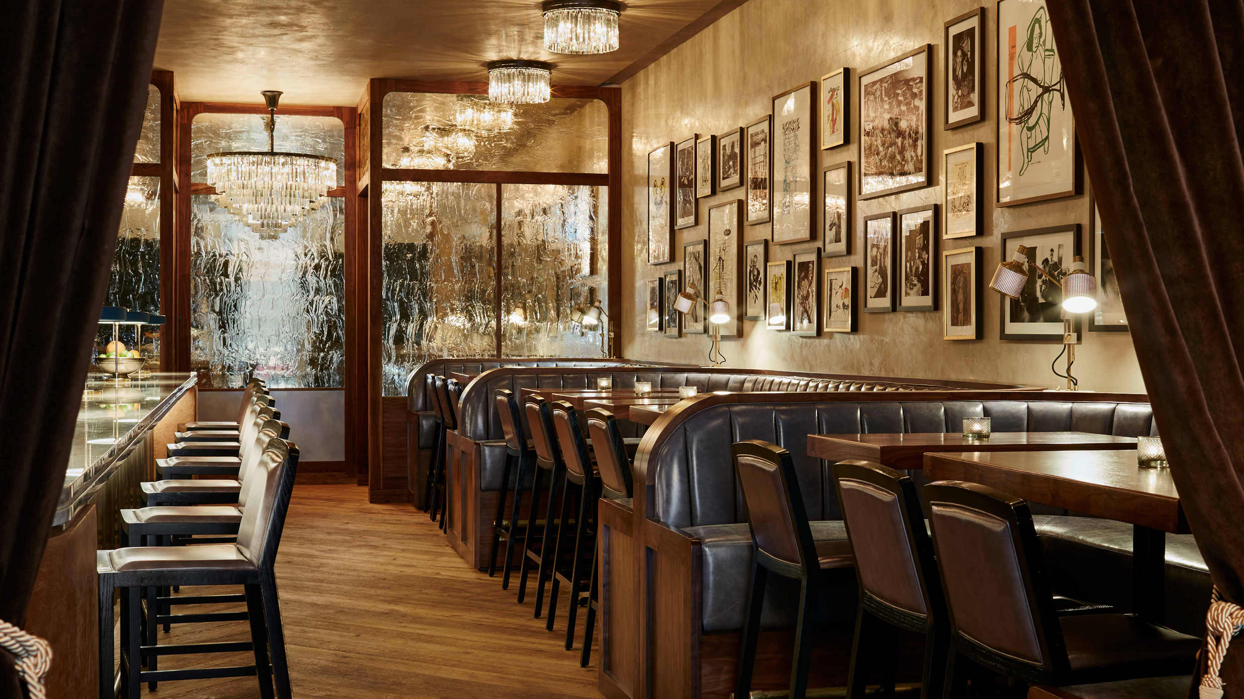 Maple & Ash dining room with leather booths, crystal chandeliers, and gallery wall