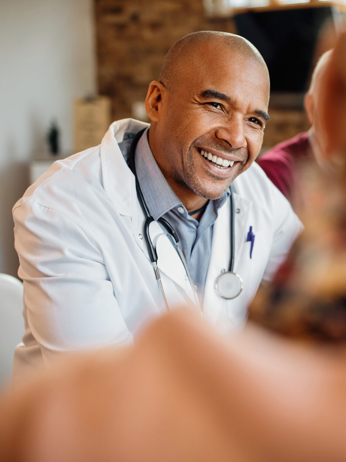 Close-up portrait of a smiling male doctor wearing a white lab coat and stethoscope.