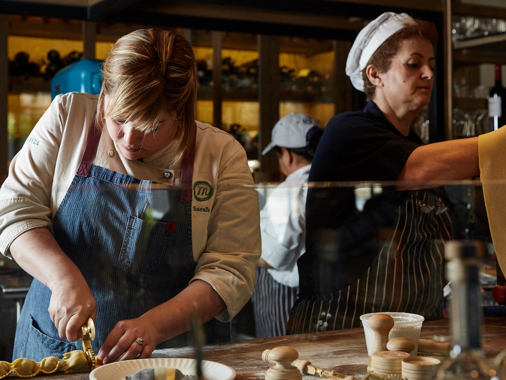 Chef Sarah preparing fresh handmade pasta in a bustling restaurant kitchen.