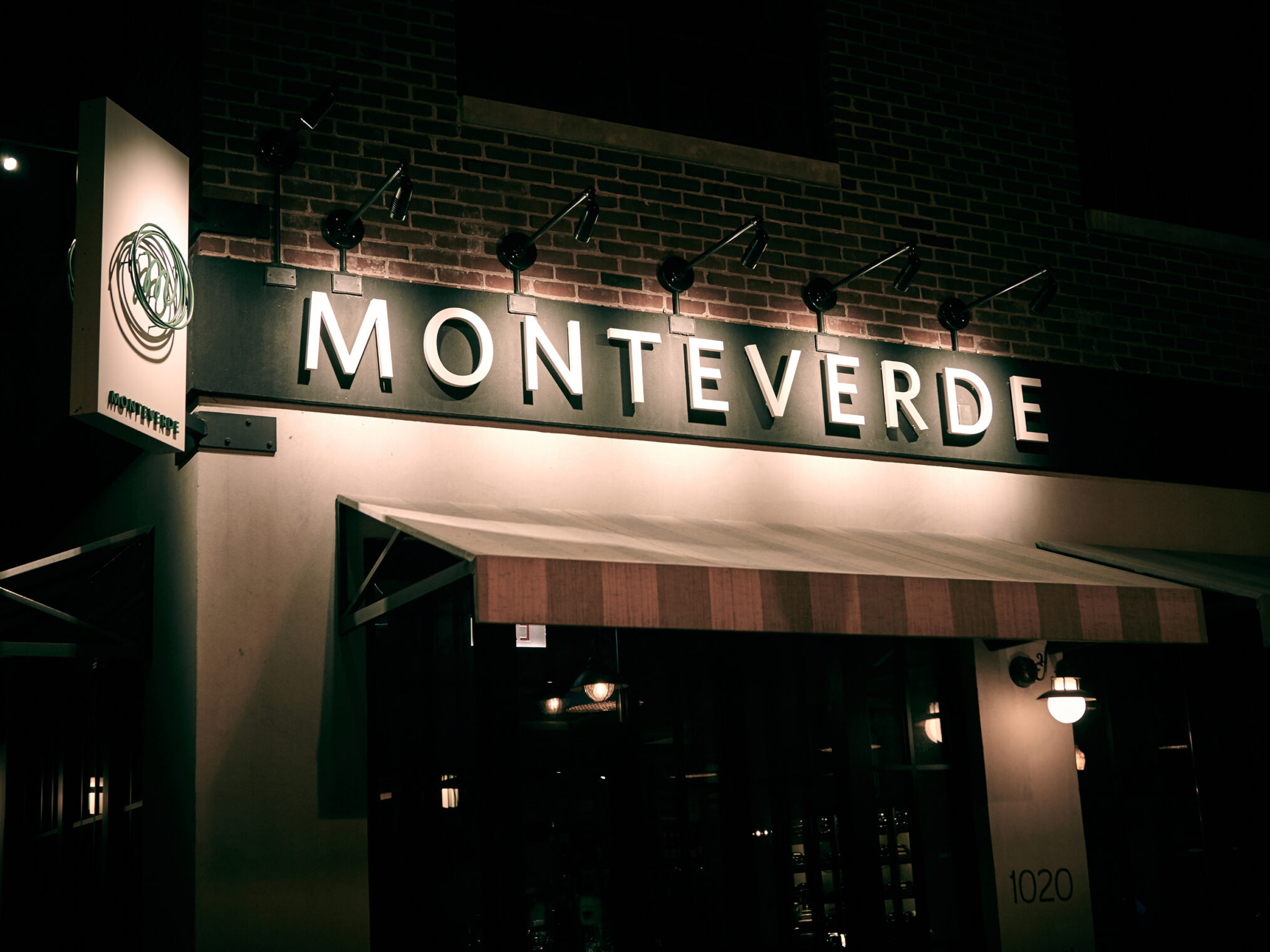 Illuminated Monteverde restaurant exterior sign and awning at night.