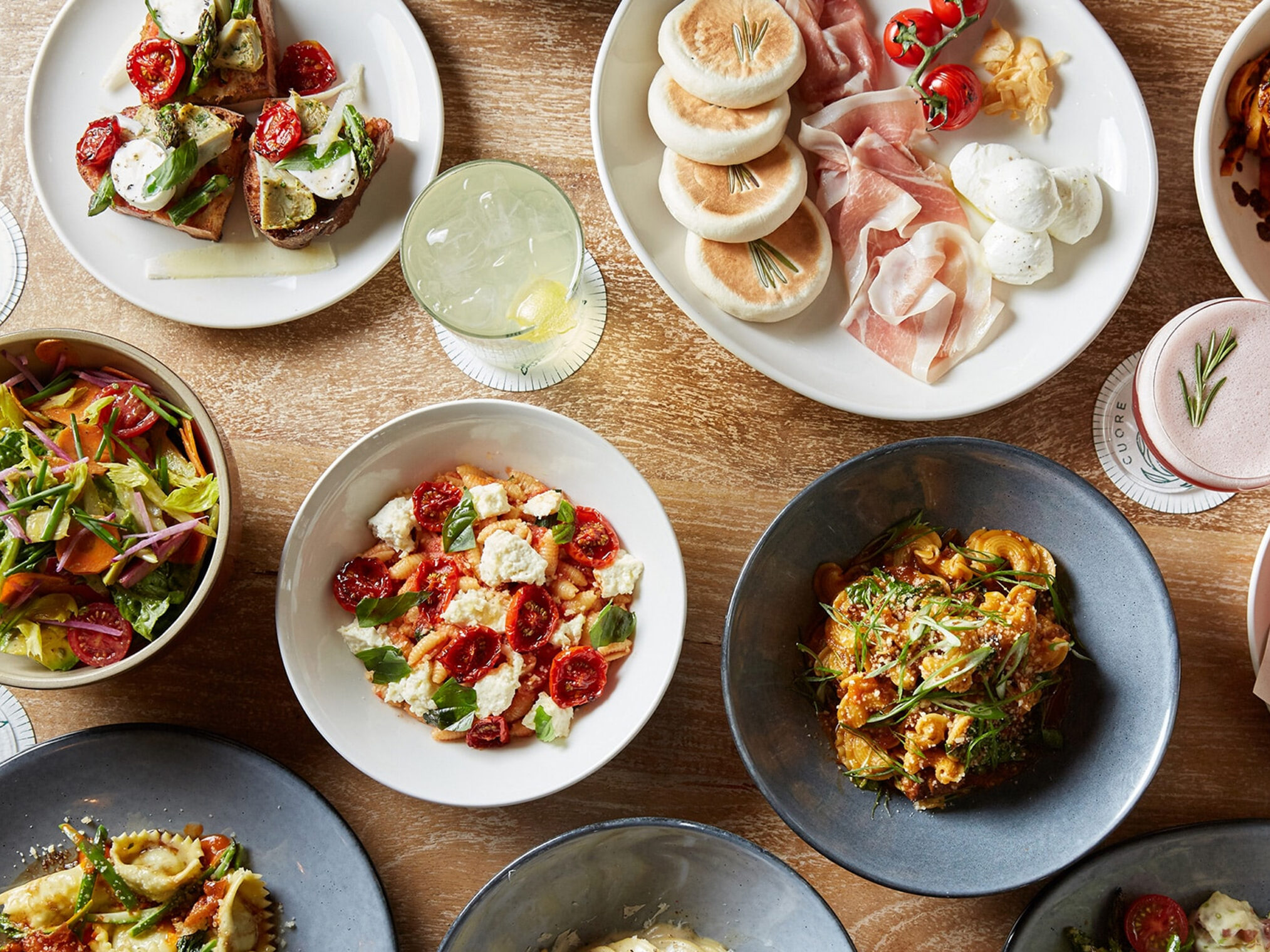 Overhead view of a table spread with various Italian pasta dishes and appetizers.