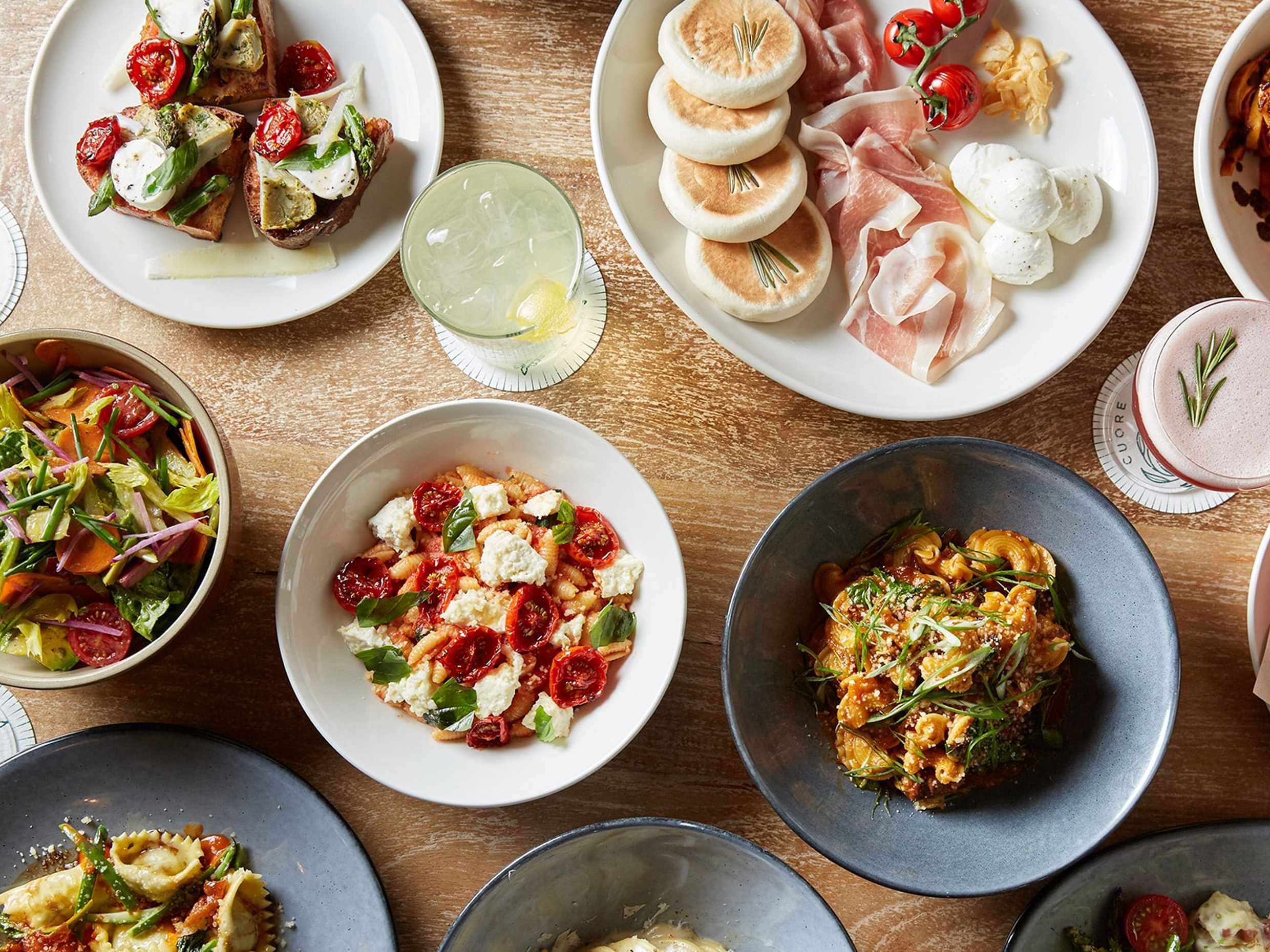 Overhead view of a table spread with various Italian pasta dishes and appetizers.