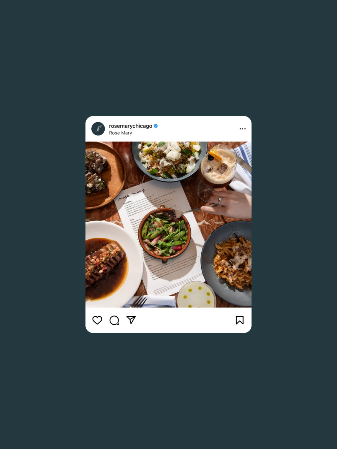 Overhead view of a restaurant table with several plated dishes, including salad, pasta, steak, a cocktail, and bread with olive oil, posted on Instagram by @rosemarychicago.
