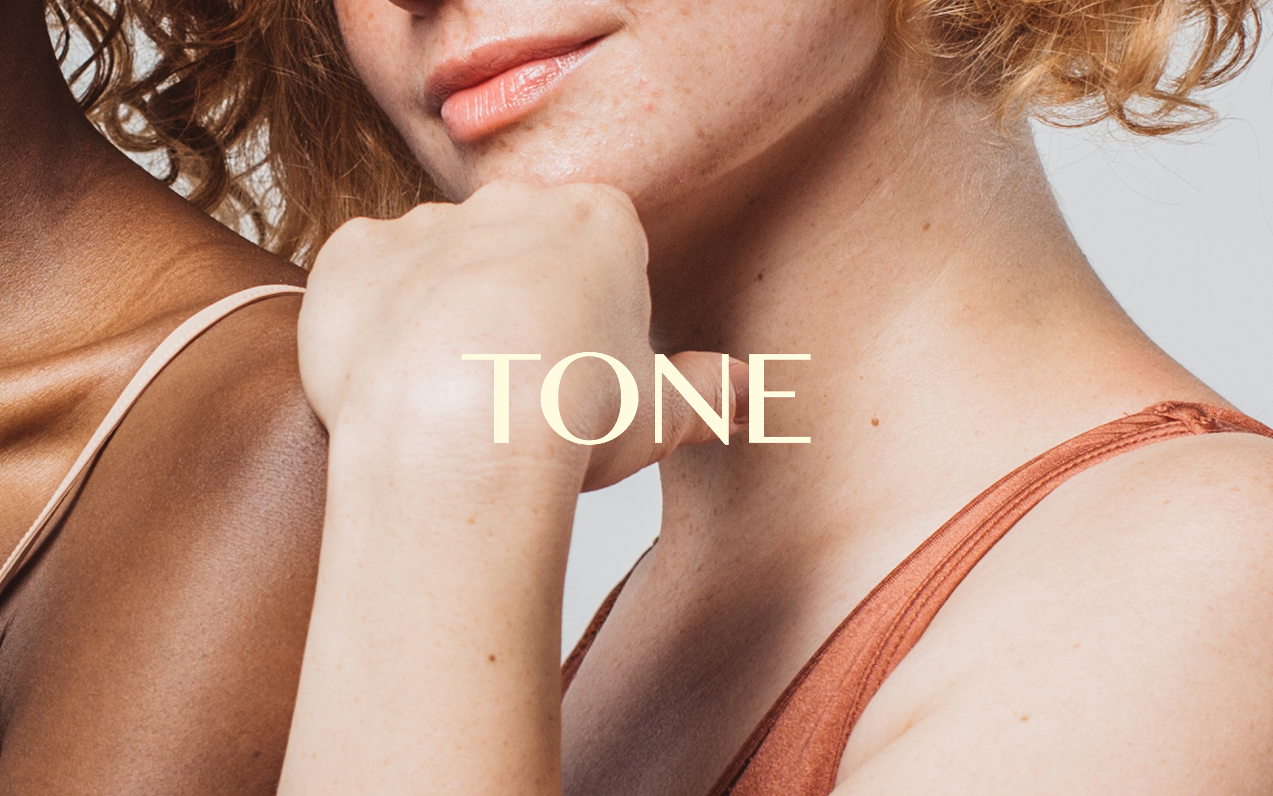 A close-up photograph of people showcasing diverse skin tones with the word "TONE" overlayed in elegant serif typography.