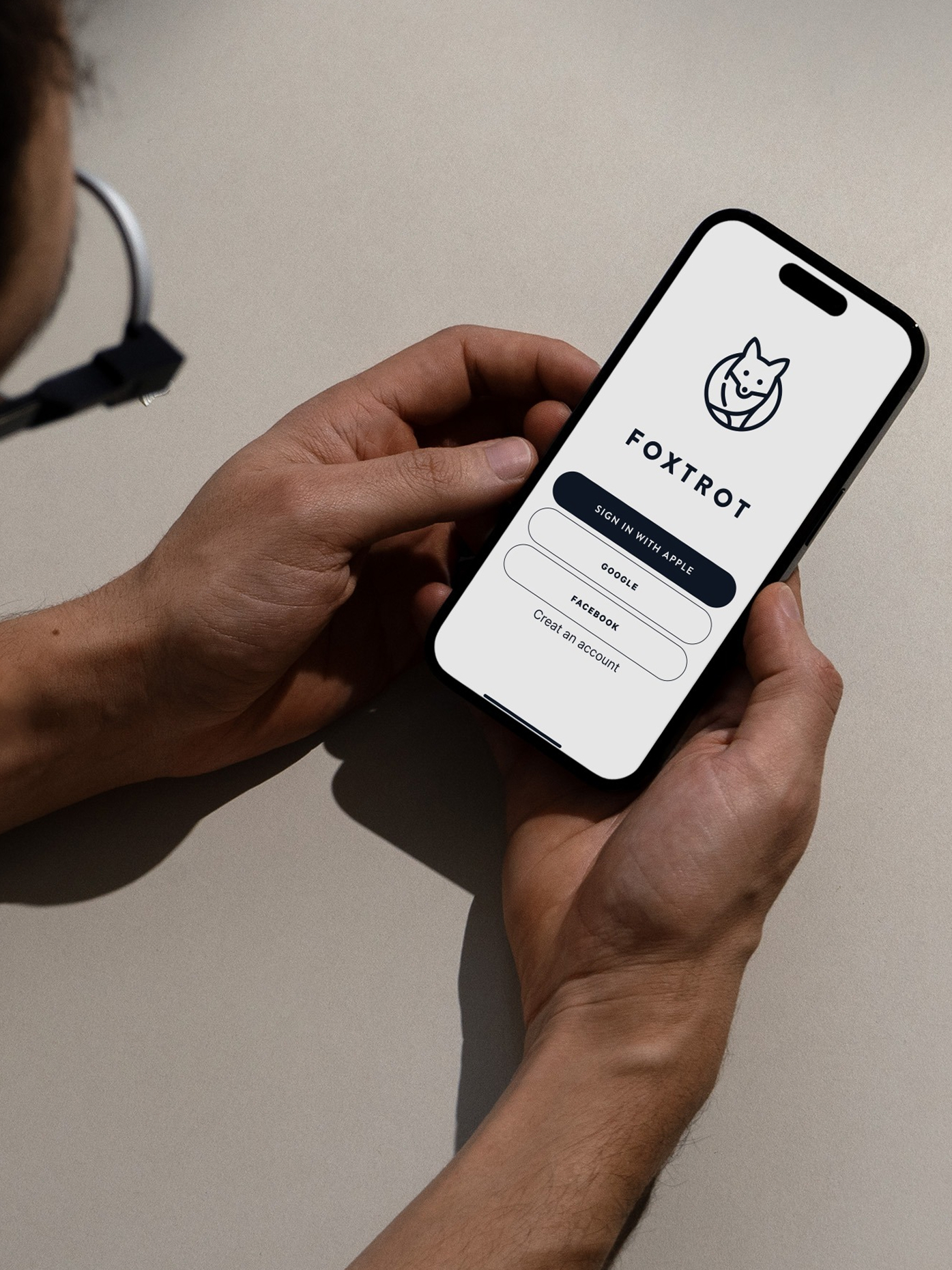 Person holding a smartphone displaying the Foxtrot mobile app login screen.