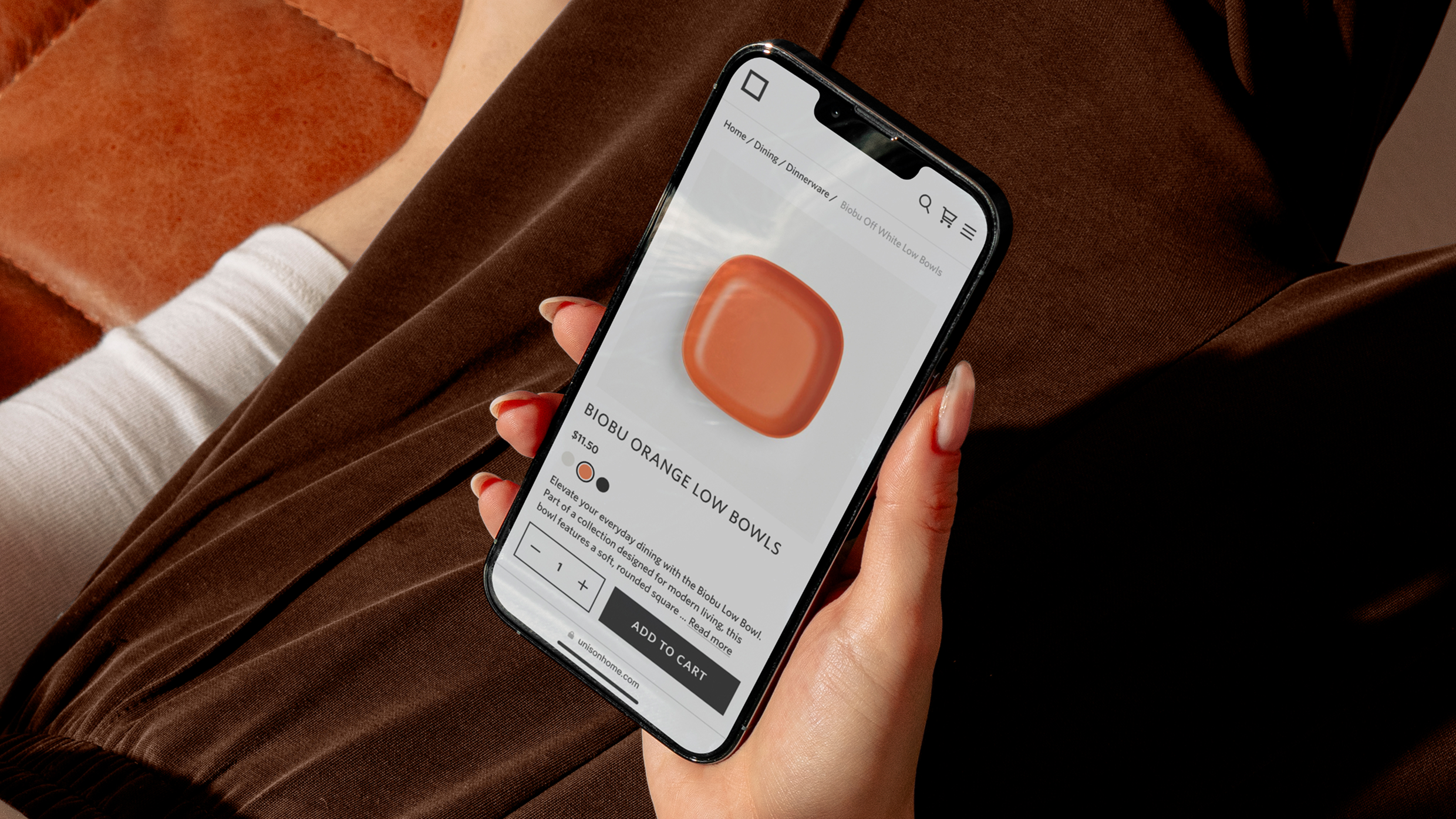 Person holding a smartphone displaying a ceramic bowl product page in a modern home decor shopping app.